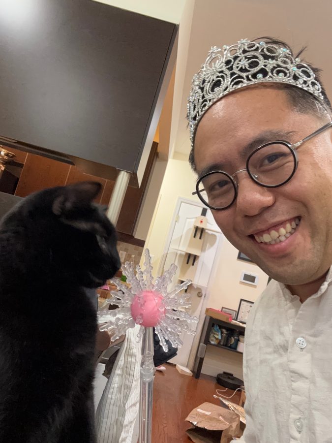 Robin wearing a tiara, holding a toy wand, with Coco the black cat